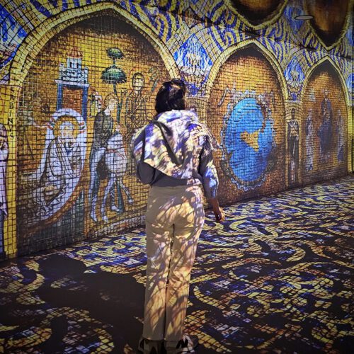 woman seen from behind in an immersive room with video mapping from floor to ceiling on the theme of the Vikings
